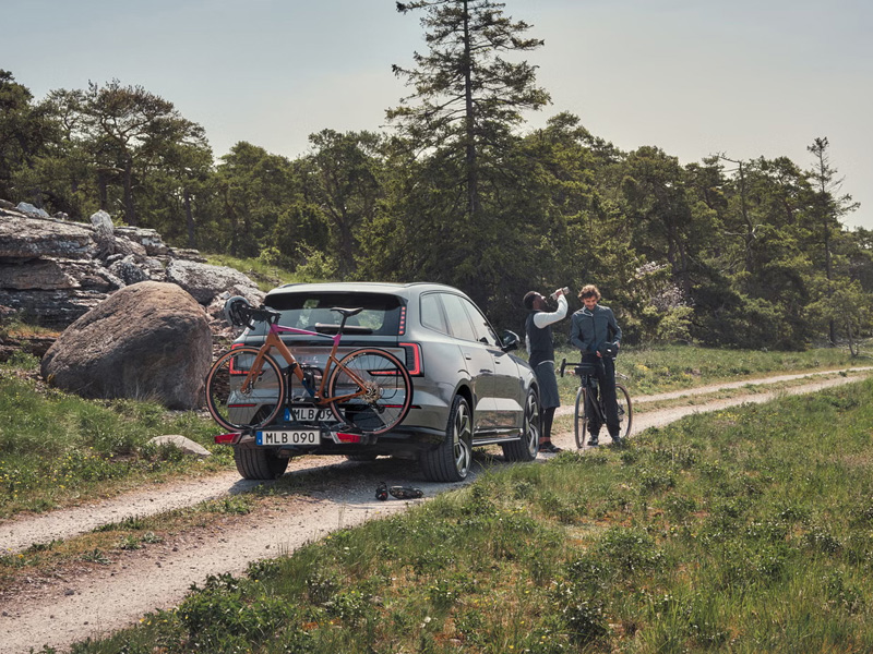 Two people standing by their Volvo with a bike rack